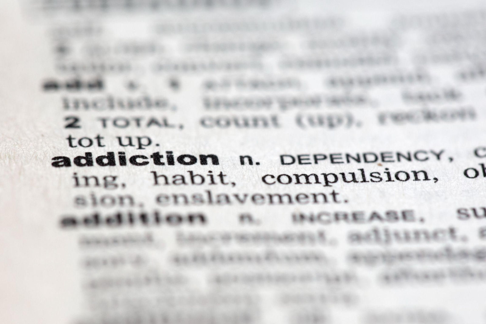 Macro close-up shot of the word addiction and its definition in a dictionary