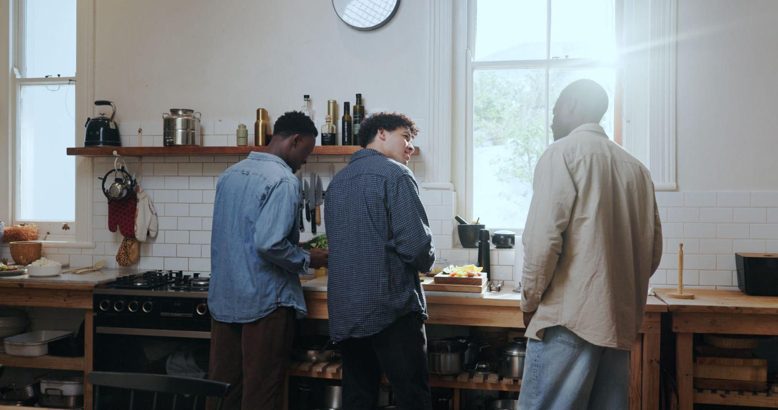 Three men preparing a meal together in a shared kitchen, demonstrating daily routines at an addiction treatment centre.